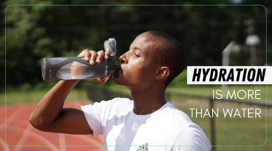 A man drinking water outside on a running track.