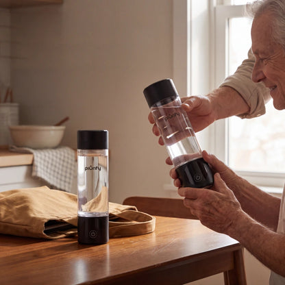 Two black PIURIFY Hydrogenator hydrogen water bottles on a kitchen table